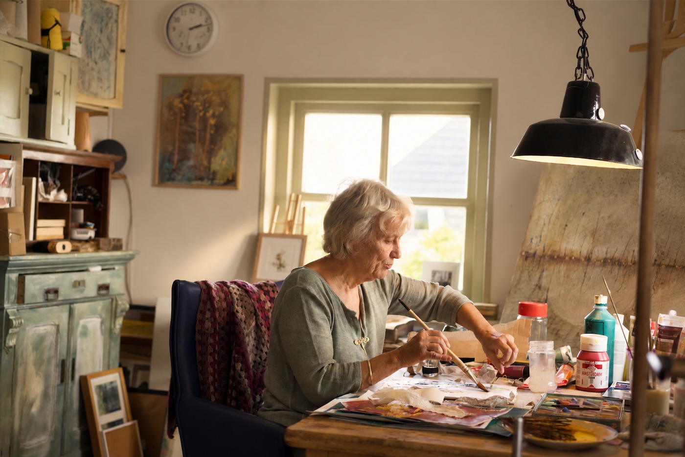 Els aan haar werktafel in het atelier, bij het raam