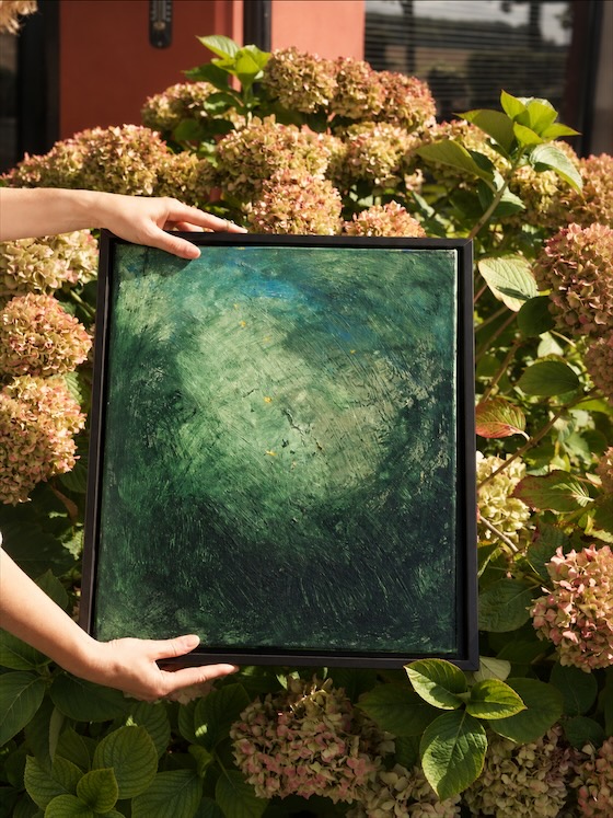 Twee handen houden een donkergroen werk voor een hortensia